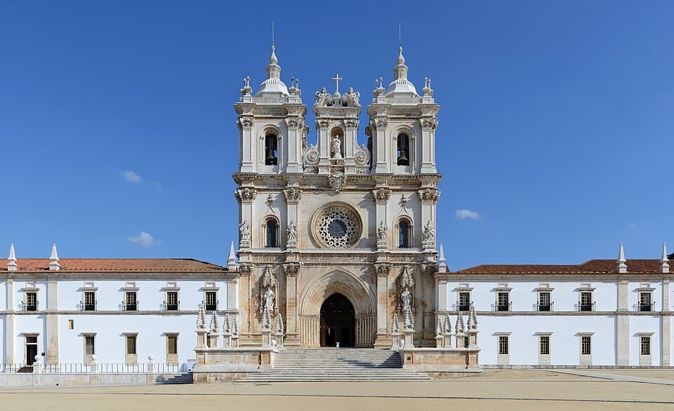 Fachada e torres do Mosteiro de Alcobaça sob o céu azul