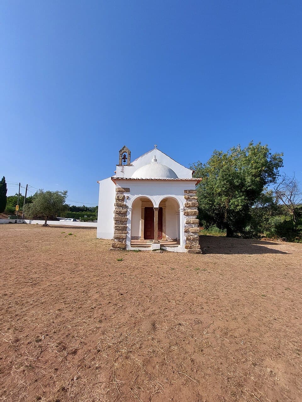 Ermida branca de Nossa Senhora do Socorro num terreiro do Carvalhal