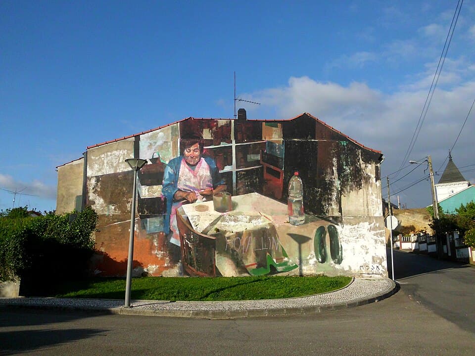 Mural de uma mulher sentada numa cozinha numa rua de Estarreja