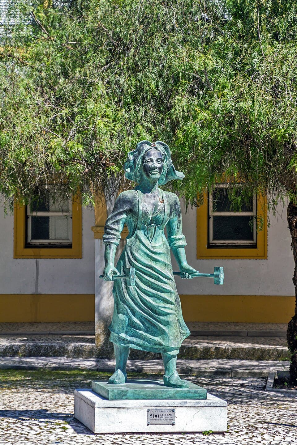 Estátua da Ferreira diante de um edifício tradicional da vila