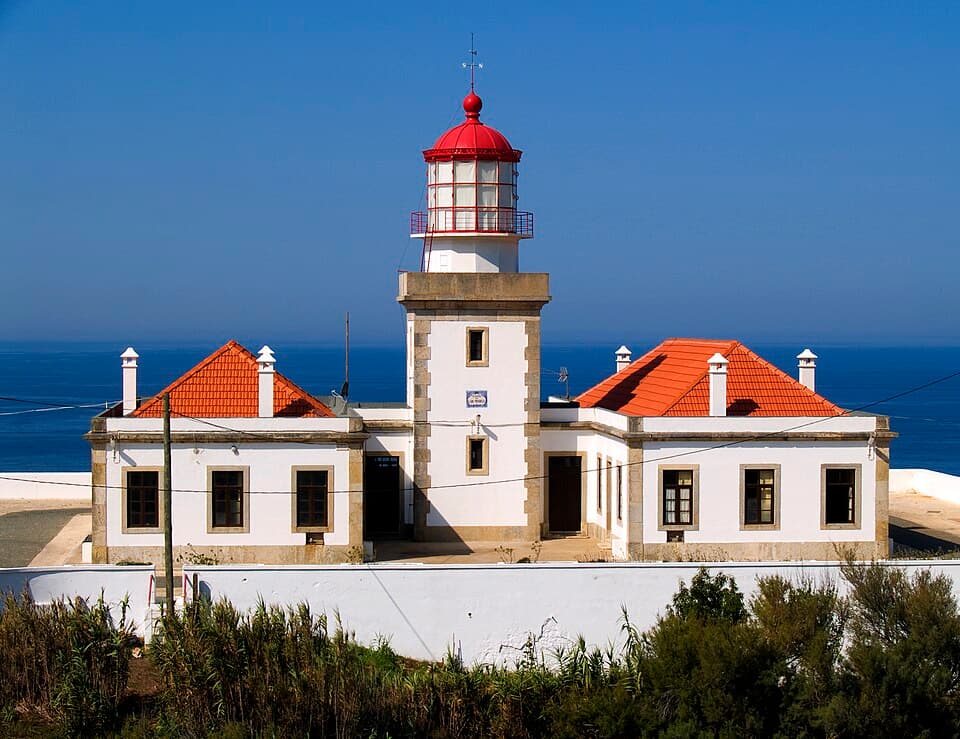 Edifício branco e torre do Farol do Cabo Mondego diante do oceano