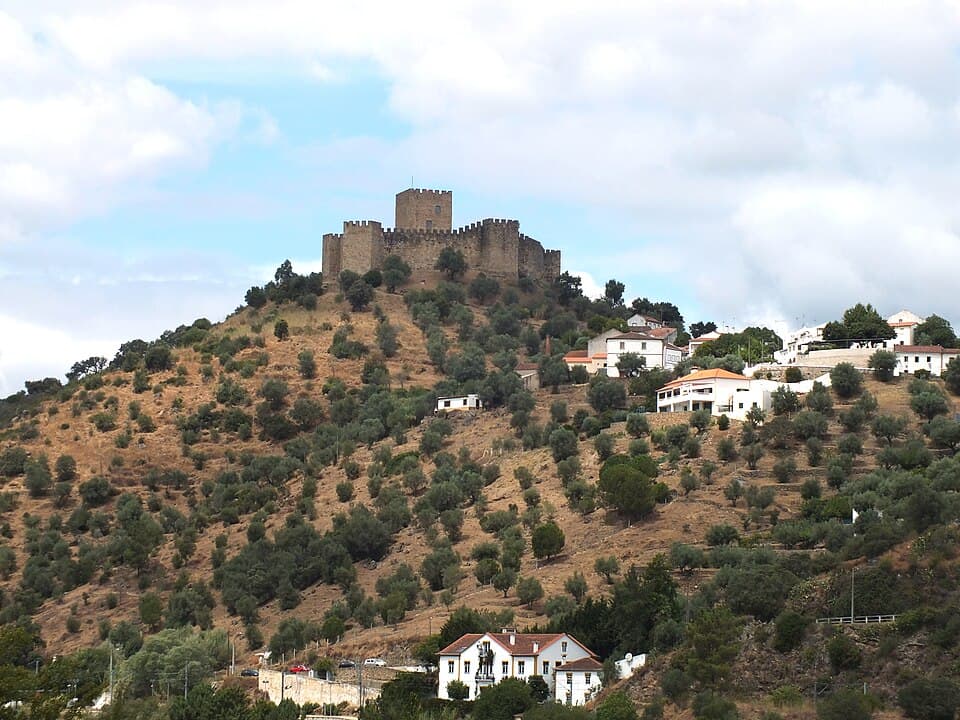 Castelo de Belver no alto da encosta sobre casas e olivais