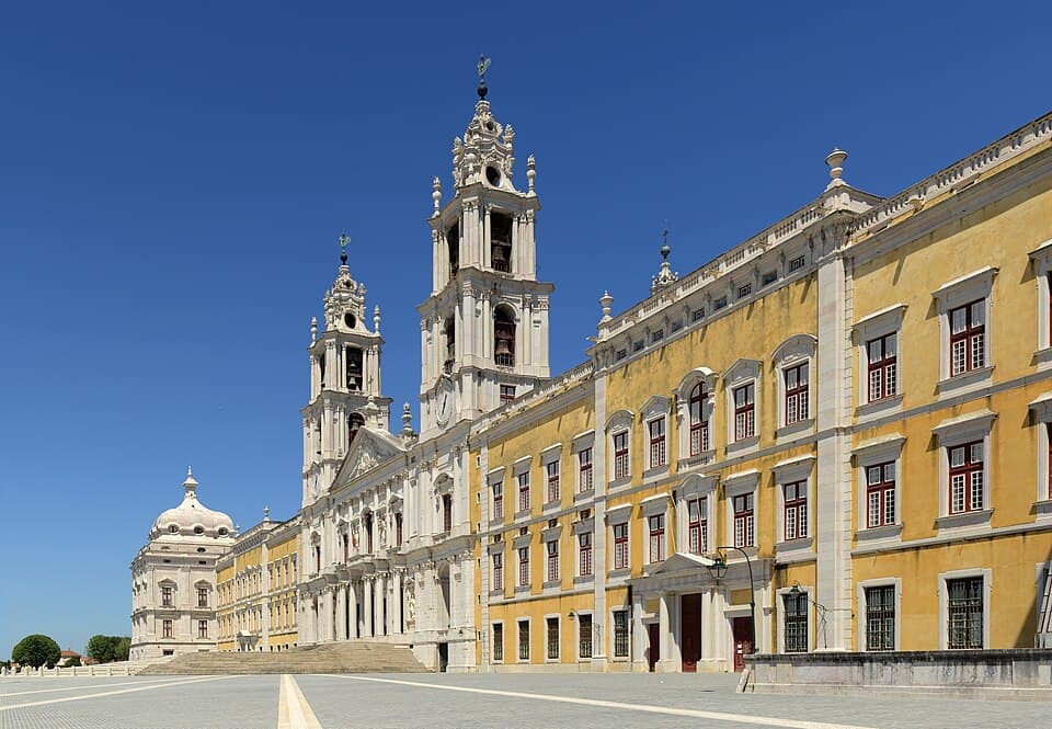 Fachada e torres sineiras do Palácio Nacional de Mafra sob o céu azul