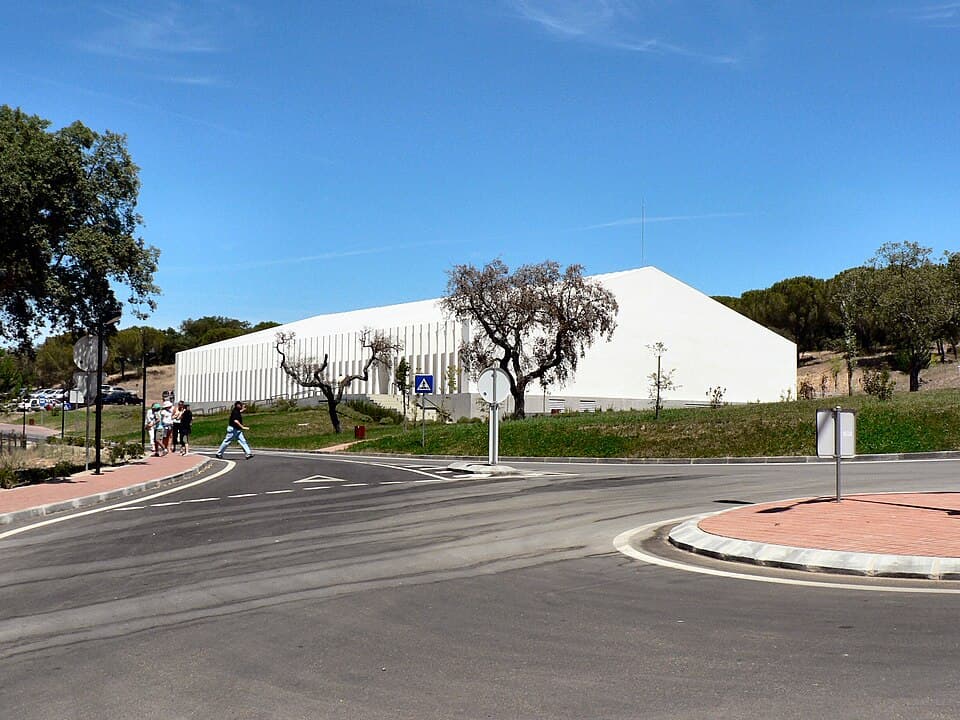 Edifício branco do Fluviário de Mora entre sobreiros e caminhos do Parque do Gameiro