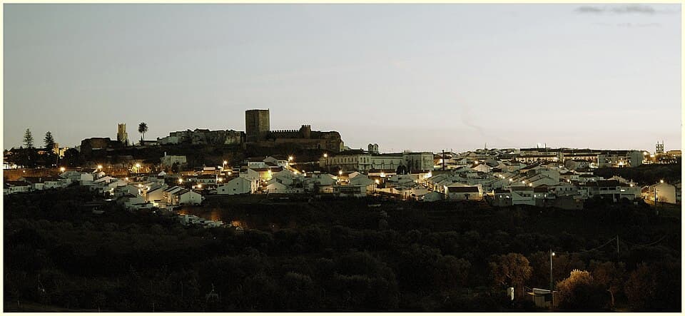 Vista panorâmica sobre o casario, o castelo e a planície de Moura ao fim da tarde
