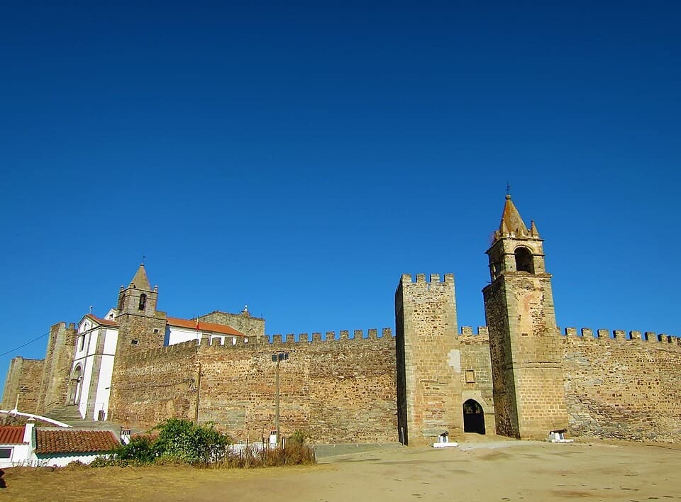 Muralha, torres e entrada do Castelo de Mourão sob céu azul