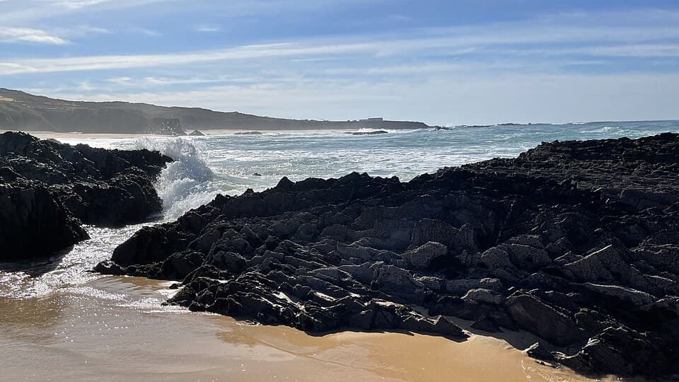 Areal, rochas escuras e ondas na Praia do Almograve, em Odemira