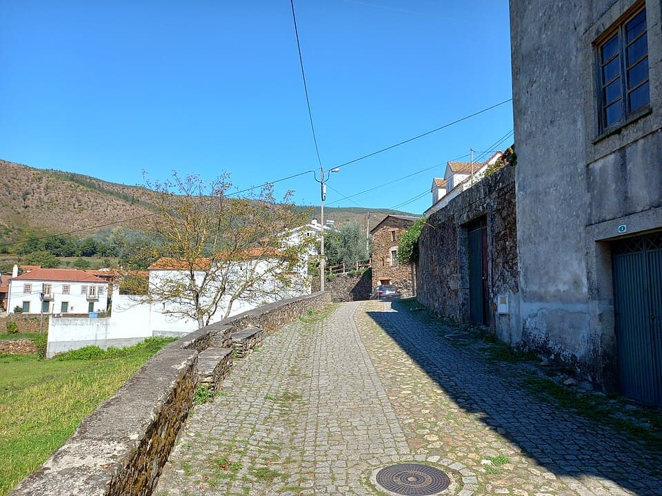 Rua empedrada entre casas em Alvoco das Várzeas