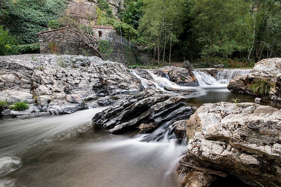 Rio Sousa entre rochas e arvoredo no Parque da Senhora do Salto