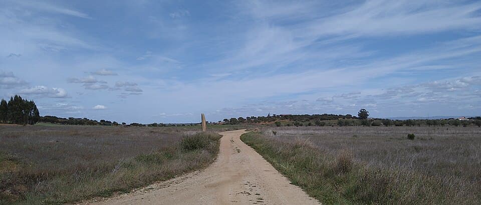 Menir do Outeiro erguido ao longe junto a um caminho rural
