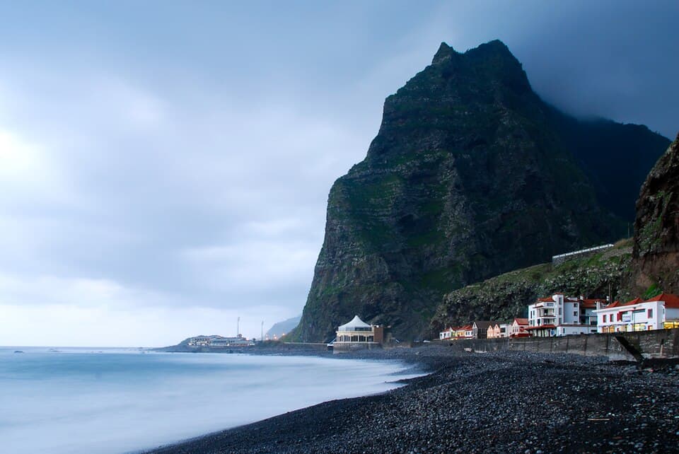 Praia de calhau de São Vicente com vila, oceano e montanha