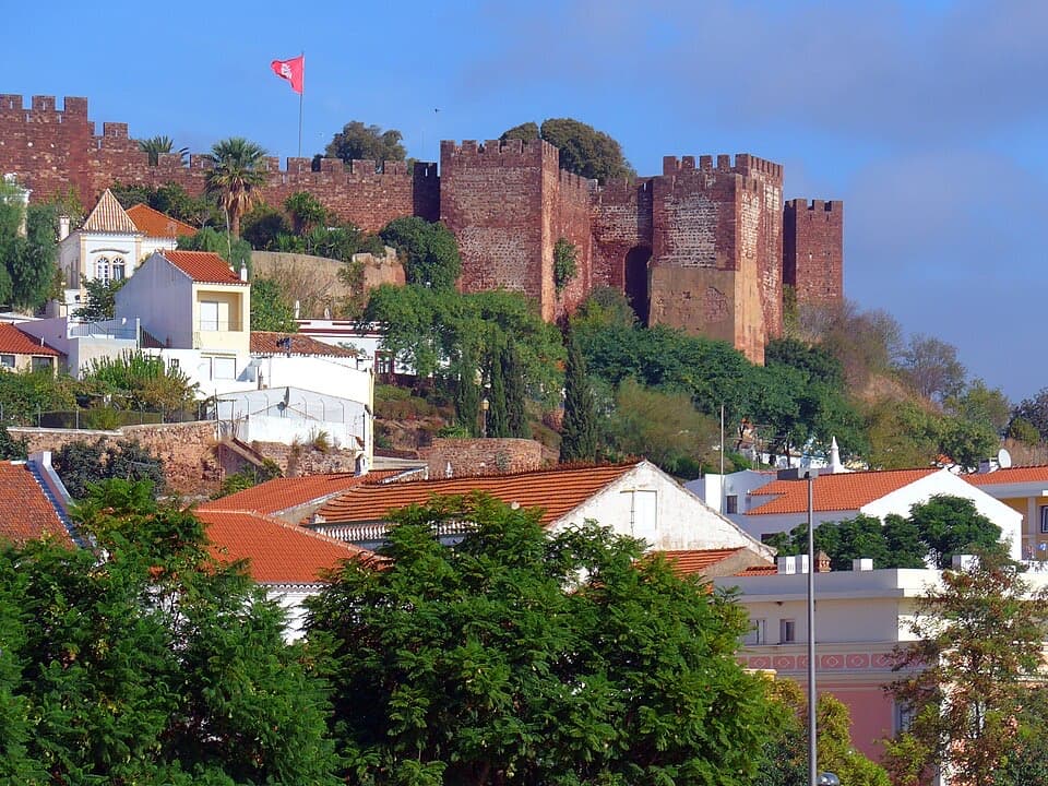 Muralhas vermelhas do Castelo de Silves acima do casario branco