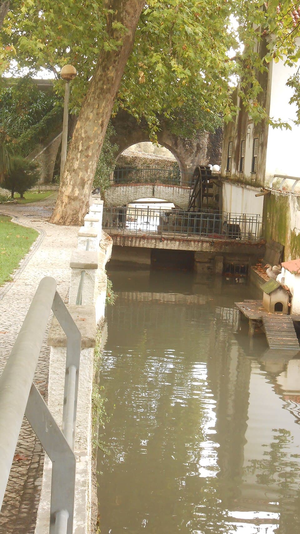 Canal do rio Anços entre árvores, muros e pequenas pontes no centro de Soure