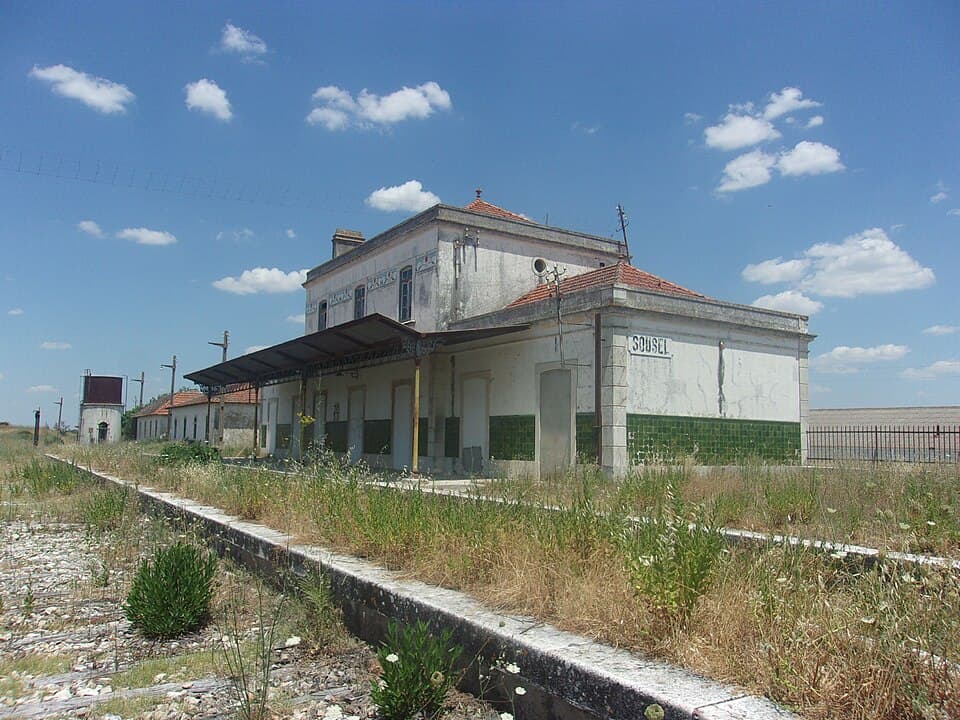 Edifício e plataforma da antiga Estação de Sousel entre vegetação espontânea