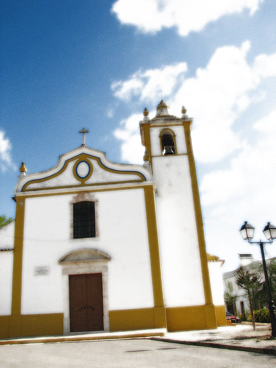Fachada branca e amarela da Igreja Matriz de Cano com cruz e torre sineira
