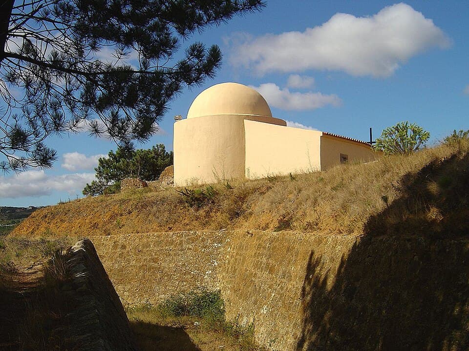 Capela de São Vicente de cúpula clara entre os taludes do forte