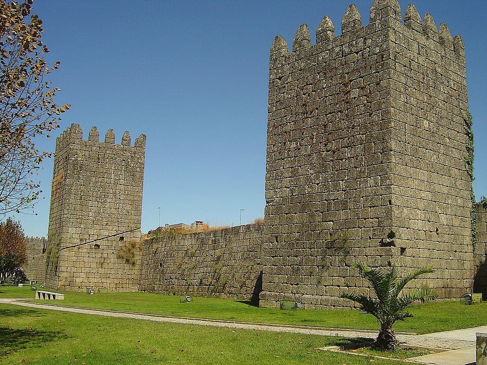 Torres e panos das muralhas de Trancoso sob céu azul