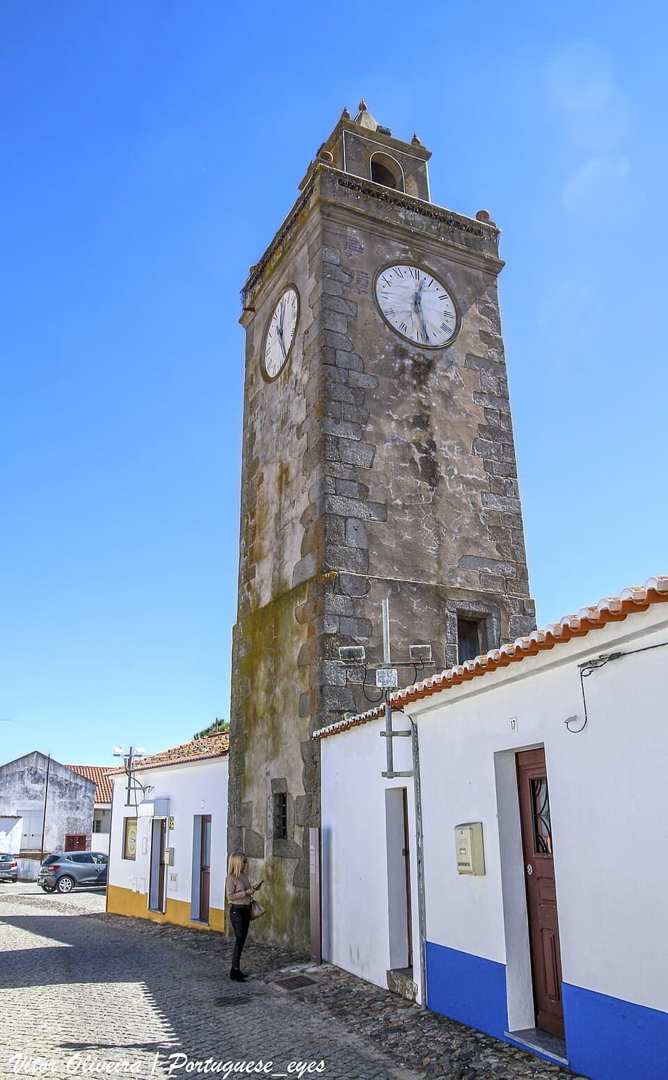 Torre do Relógio de pedra acima do casario branco da Vidigueira