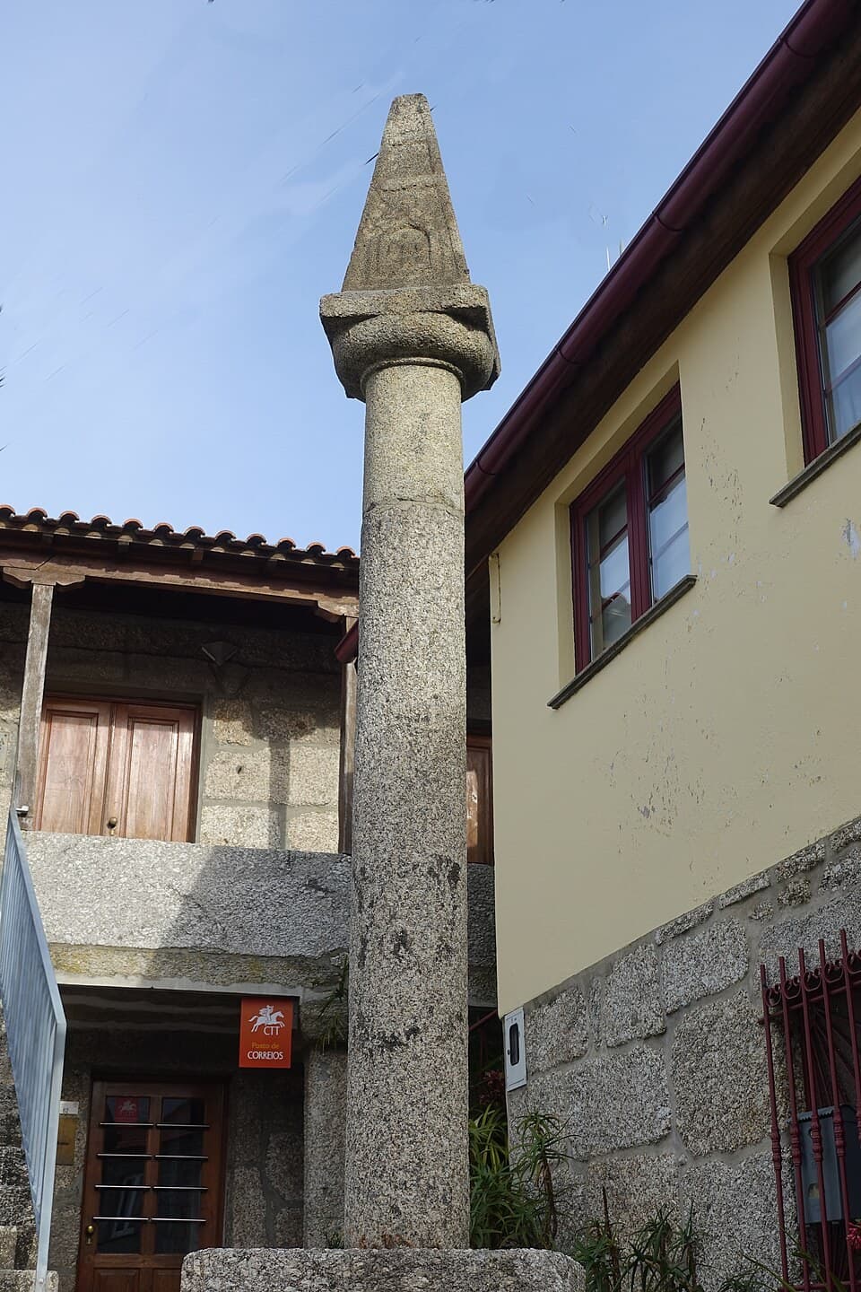 Pelourinho de pedra de Rossas entre edifícios da freguesia