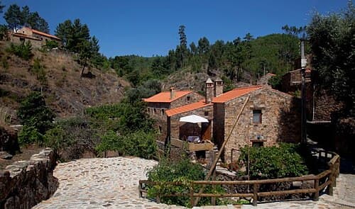 Casas de xisto da aldeia de Água Formosa numa encosta arborizada
