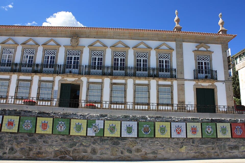 Fachada branca com janelas alinhadas e brasão do Solar dos Condes de Vinhais
