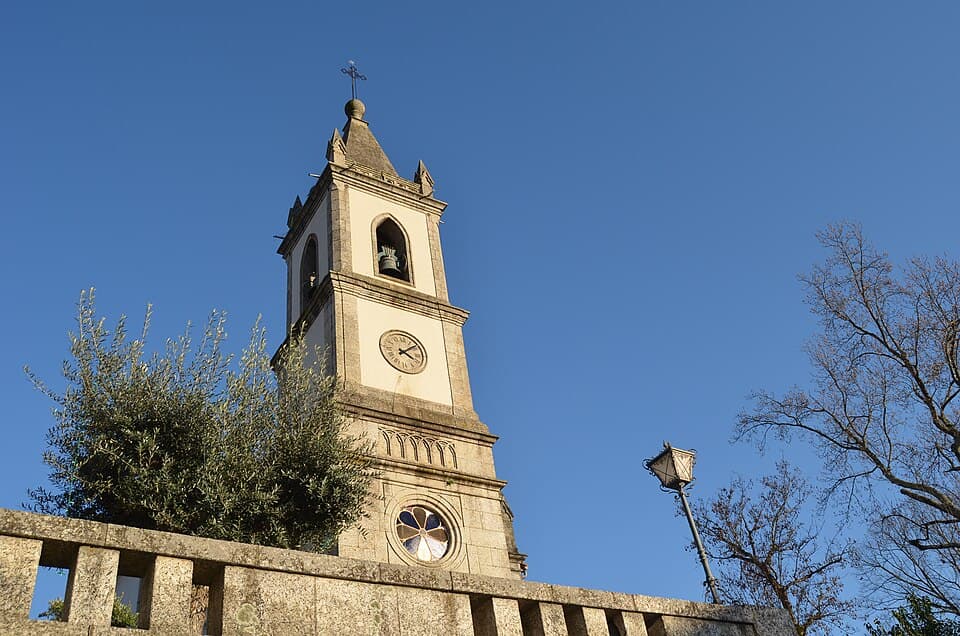Torre de granito da Igreja Paroquial de Caldas de Vizela sob céu azul